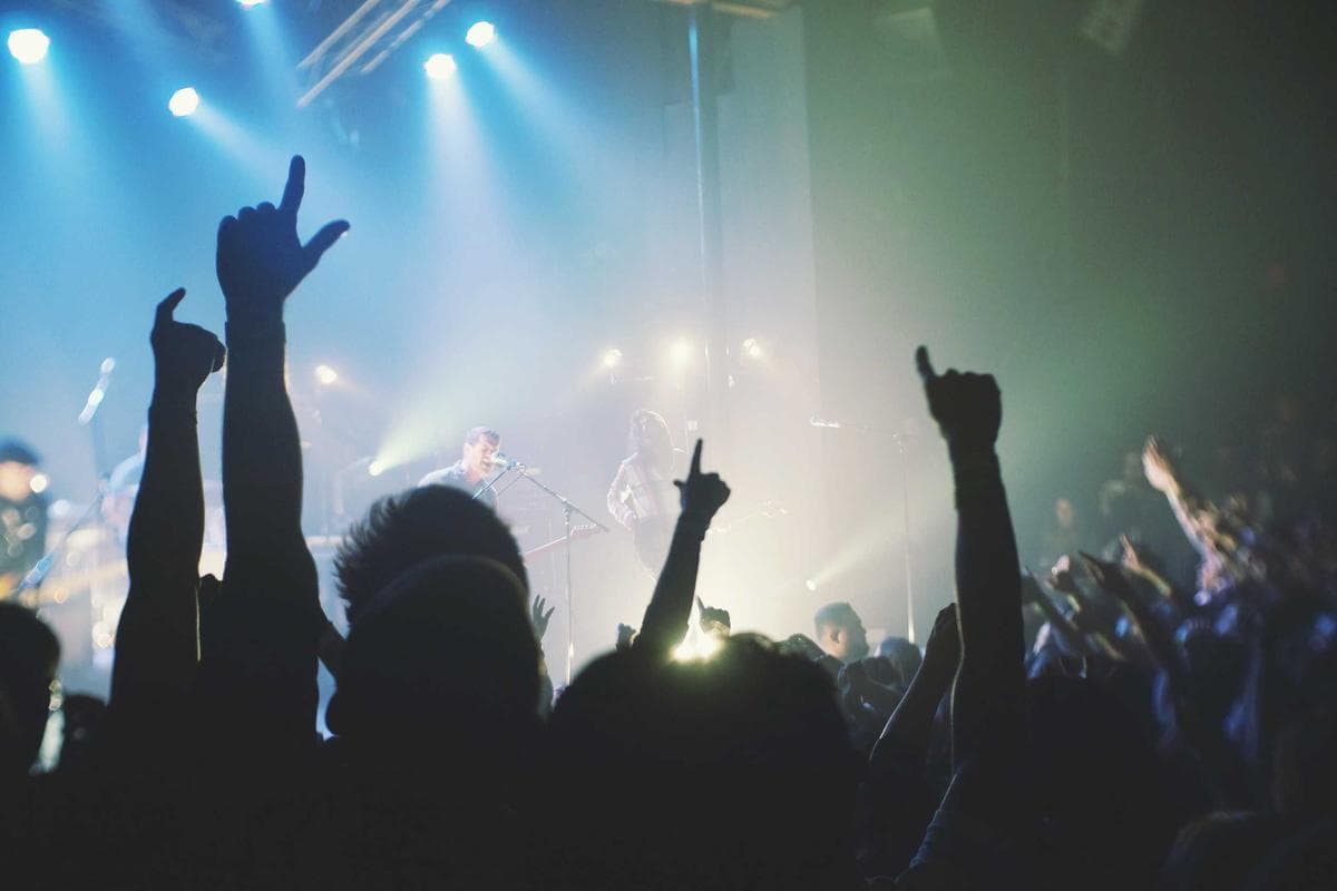 Hands raised at a night gathering as the stream goes live