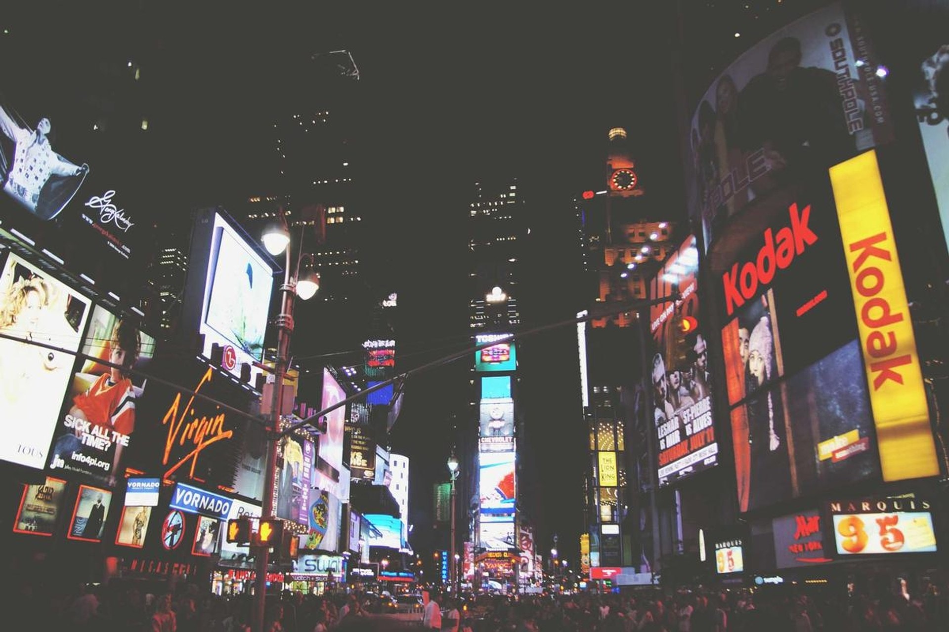 Night city street lit by neon signs, seen mid-walk